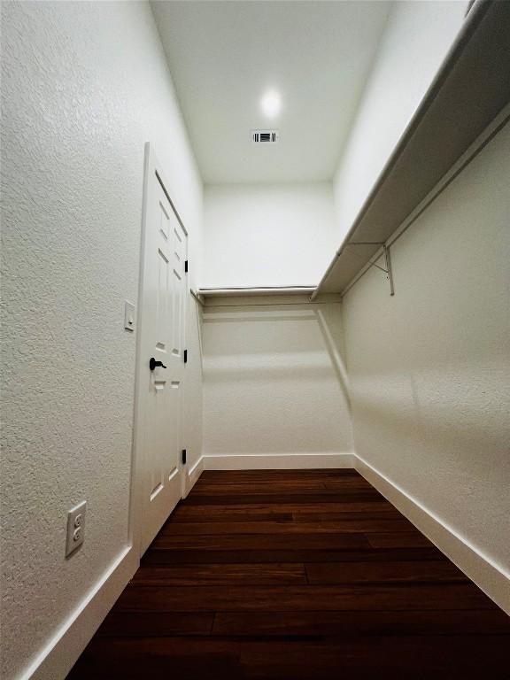 spacious closet featuring visible vents and dark wood-style flooring