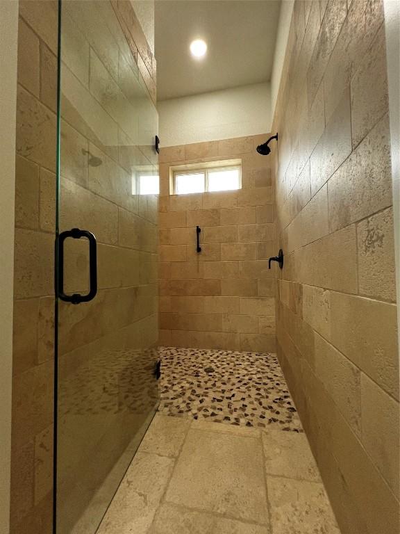 bathroom with stone finish flooring, recessed lighting, and a stall shower