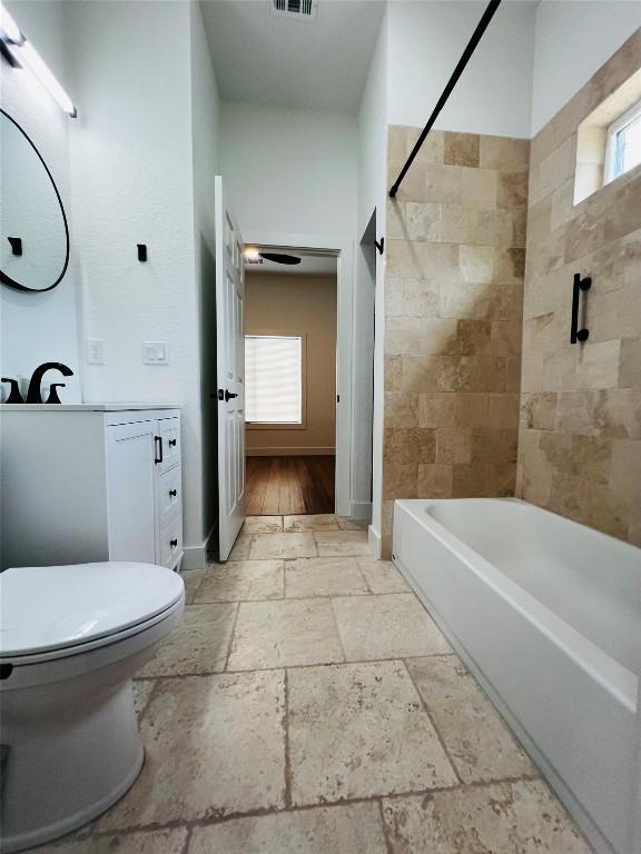 bathroom with toilet, visible vents, a wealth of natural light, and stone tile flooring