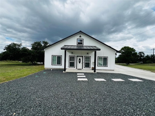 view of front of property with metal roof, a standing seam roof, a front yard, and board and batten siding
