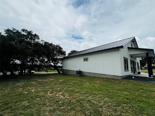 view of home's exterior featuring board and batten siding, a standing seam roof, metal roof, a lawn, and central AC unit