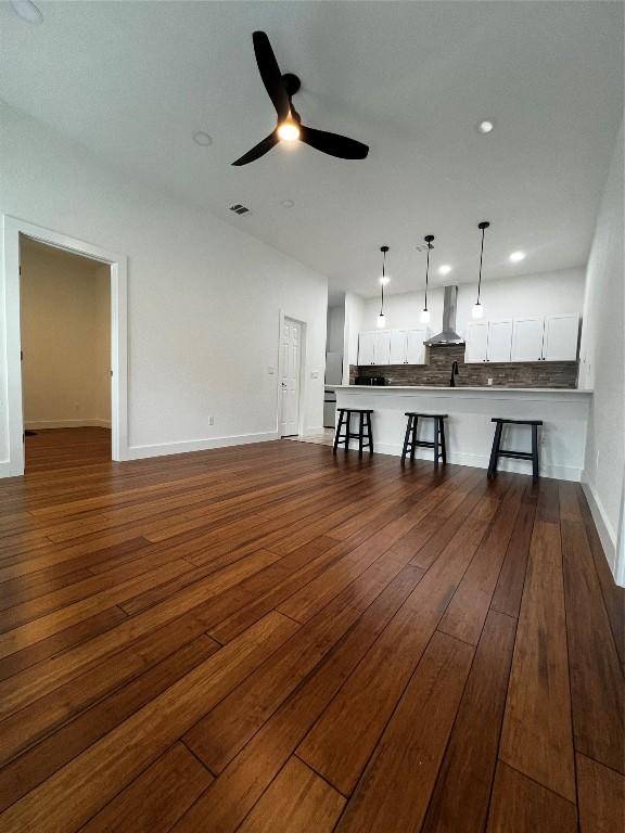 unfurnished living room with recessed lighting, a ceiling fan, visible vents, baseboards, and dark wood finished floors
