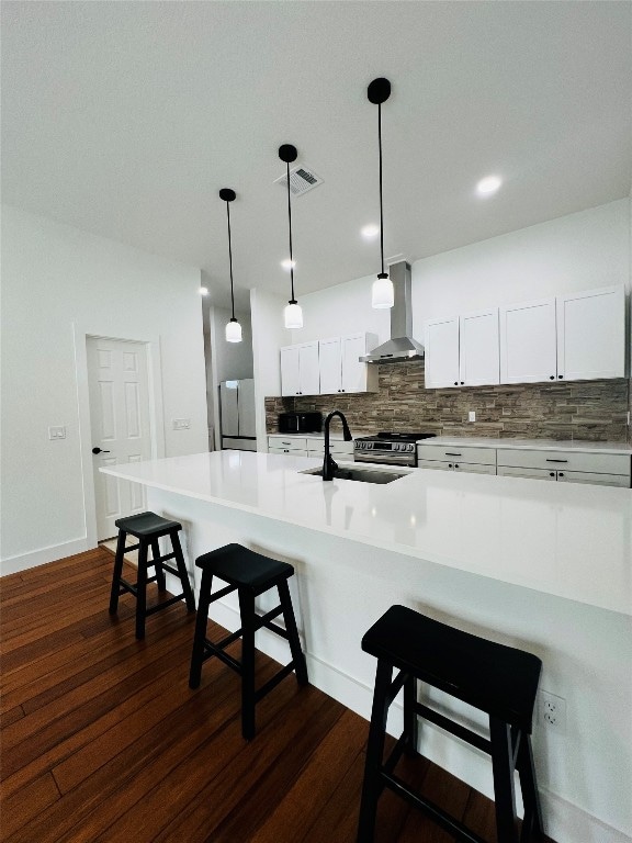 kitchen featuring white cabinetry, dark hardwood / wood-style floors, appliances with stainless steel finishes, wall chimney exhaust hood, and sink