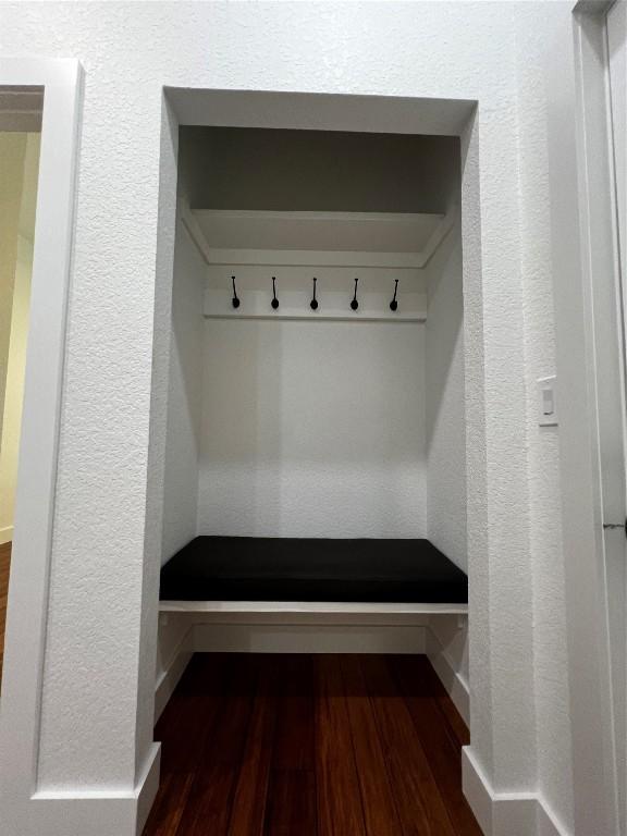 mudroom with dark wood-style floors and a textured wall