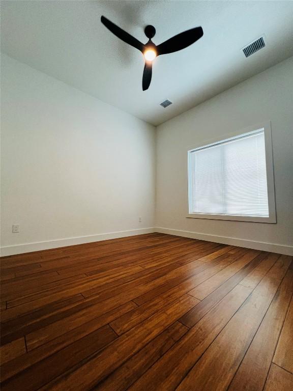 empty room with baseboards, visible vents, ceiling fan, and wood-type flooring