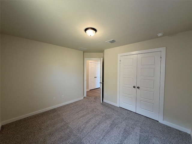 unfurnished bedroom with dark carpet and a closet