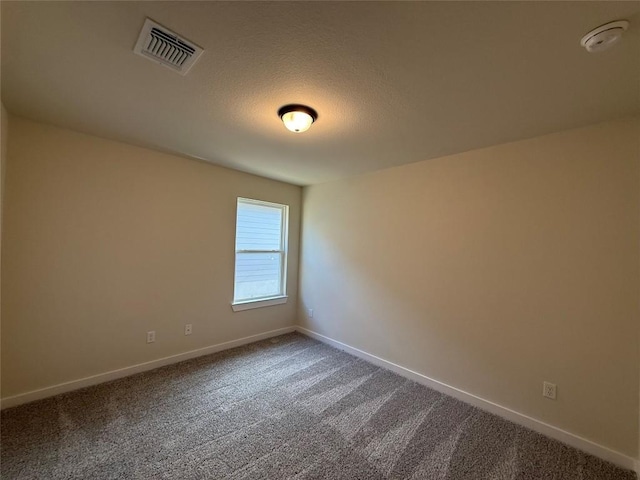 carpeted empty room featuring a textured ceiling