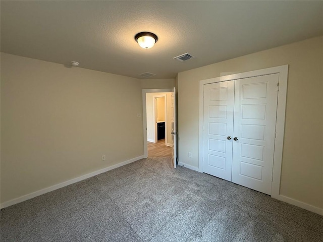 unfurnished bedroom featuring carpet, a textured ceiling, and a closet