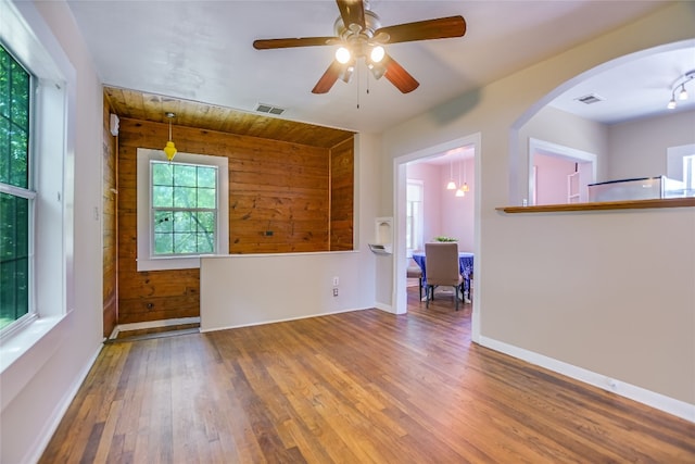 unfurnished room featuring ceiling fan, hardwood / wood-style floors, and wooden walls