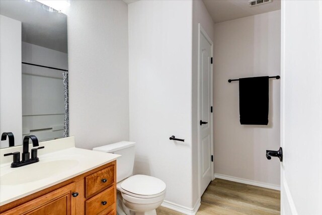 bathroom with hardwood / wood-style flooring, vanity, and toilet