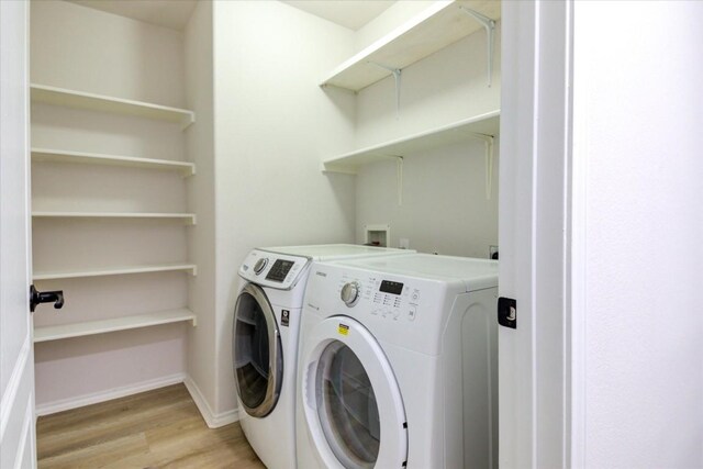 washroom with washing machine and dryer and light hardwood / wood-style floors