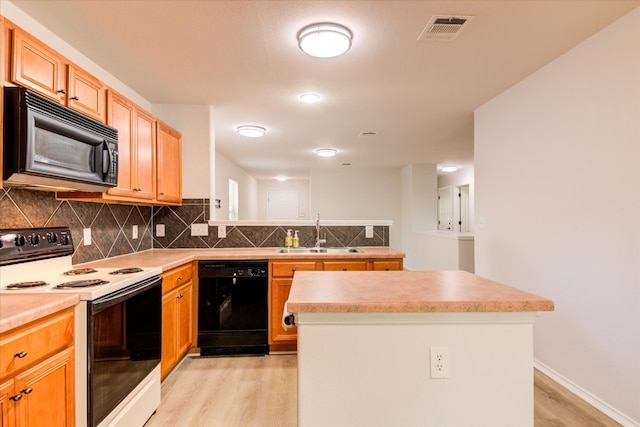 kitchen with sink, a center island, light hardwood / wood-style flooring, and black appliances