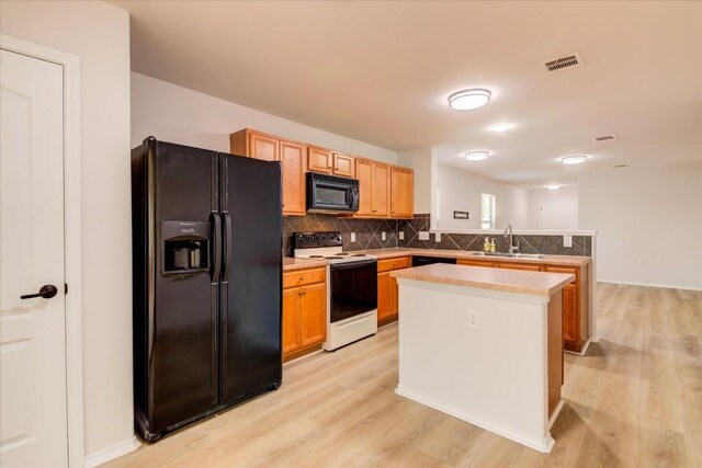 kitchen featuring sink, a center island, tasteful backsplash, black appliances, and light wood-type flooring