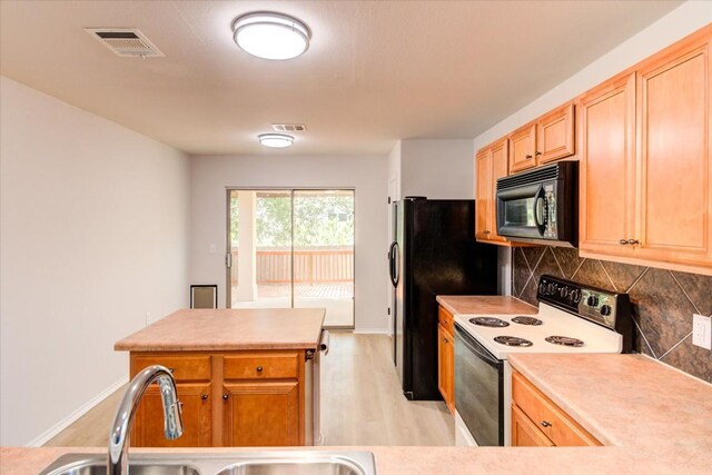 kitchen featuring sink, light wood-type flooring, tasteful backsplash, and black appliances