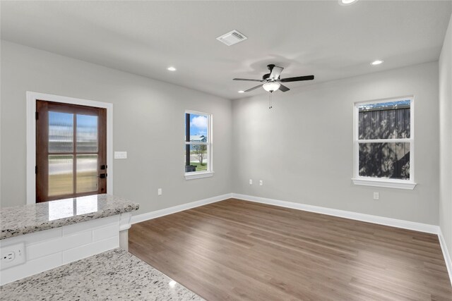 unfurnished room featuring a wealth of natural light, ceiling fan, and hardwood / wood-style flooring