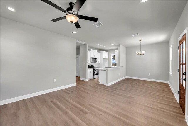 unfurnished living room with ceiling fan with notable chandelier and light hardwood / wood-style floors