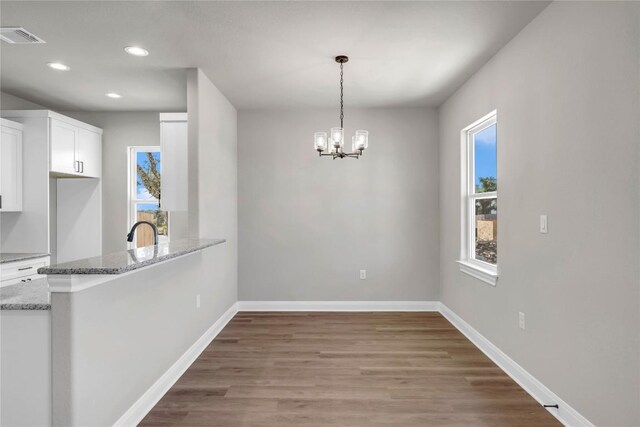 unfurnished dining area with an inviting chandelier, hardwood / wood-style floors, and sink