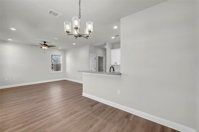 unfurnished living room featuring sink, ceiling fan with notable chandelier, and hardwood / wood-style floors