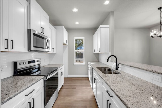 kitchen featuring pendant lighting, stainless steel appliances, sink, and white cabinetry