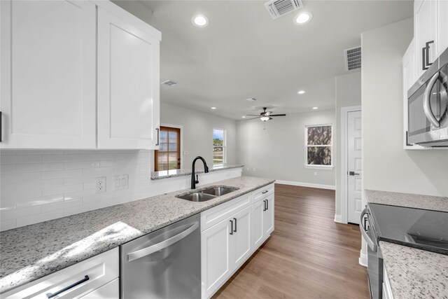 kitchen featuring appliances with stainless steel finishes, white cabinets, light wood-type flooring, ceiling fan, and sink