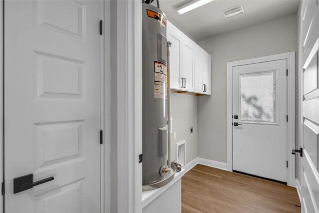 clothes washing area with electric water heater, cabinets, light wood-type flooring, and electric dryer hookup