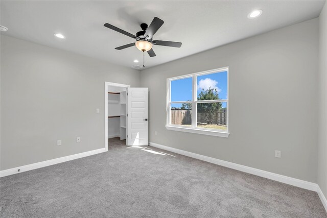 unfurnished bedroom with a spacious closet, ceiling fan, and carpet flooring