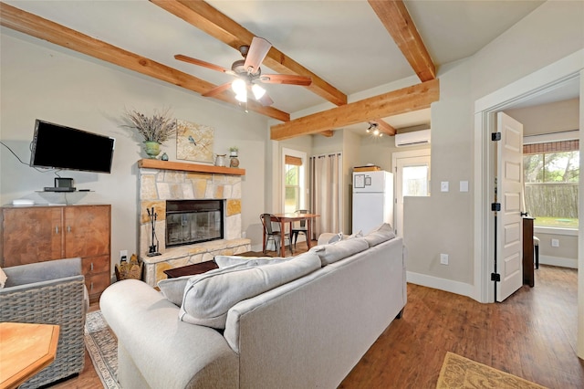 living room featuring beam ceiling, a wall mounted AC, wood-type flooring, and a healthy amount of sunlight