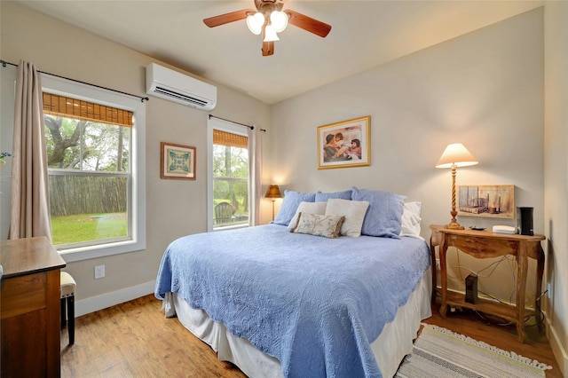 bedroom with ceiling fan, light wood-type flooring, and a wall mounted air conditioner