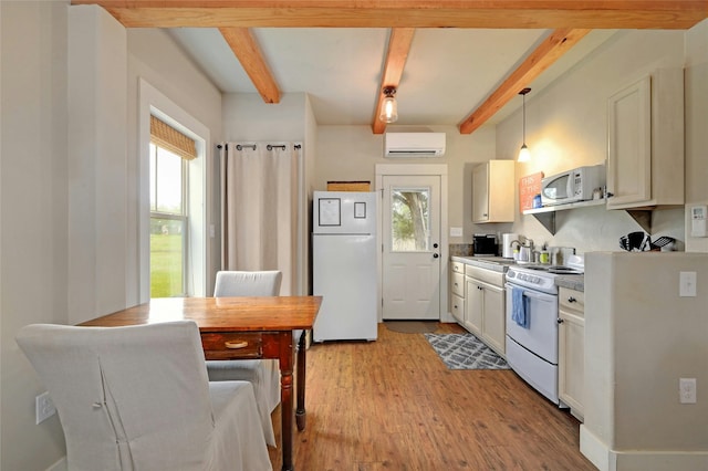 kitchen with decorative light fixtures, white appliances, a wall mounted AC, and a healthy amount of sunlight