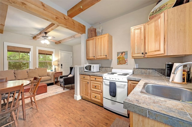 kitchen with sink, white appliances, light brown cabinets, and beamed ceiling