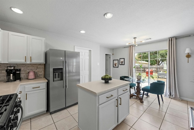 kitchen featuring gas stove, backsplash, light tile patterned flooring, and stainless steel refrigerator with ice dispenser