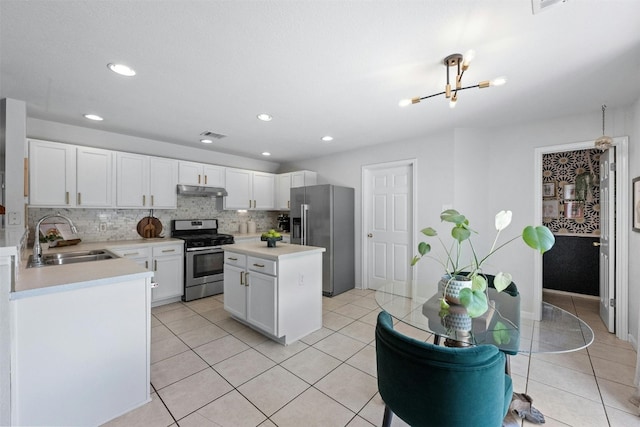 kitchen with a kitchen island, tasteful backsplash, white cabinetry, appliances with stainless steel finishes, and sink