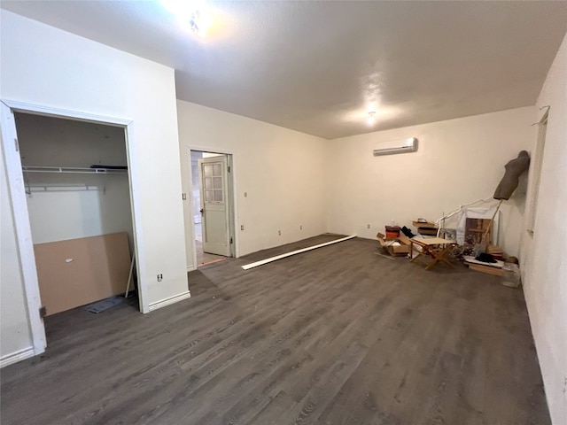 unfurnished bedroom with a wall unit AC, a closet, and dark wood-type flooring