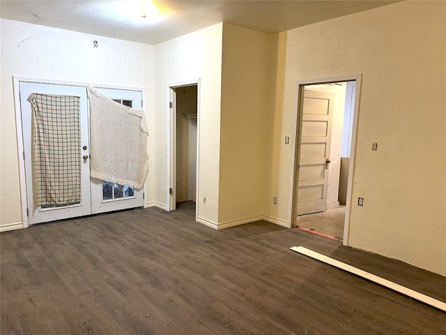 unfurnished bedroom with dark wood-type flooring, a closet, and a spacious closet