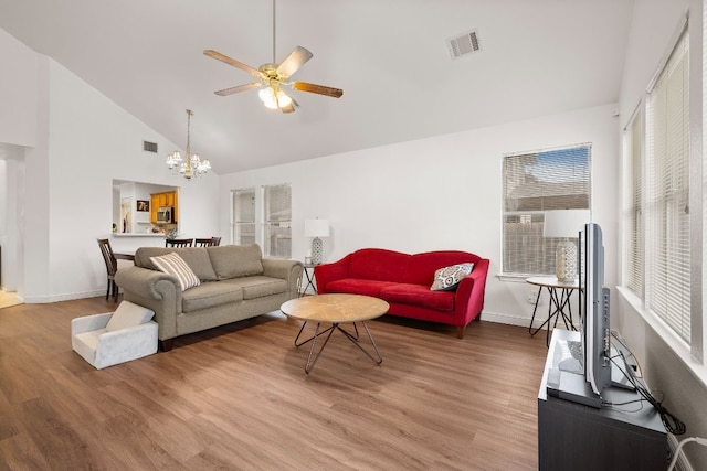 living room with a wealth of natural light, hardwood / wood-style floors, and ceiling fan with notable chandelier