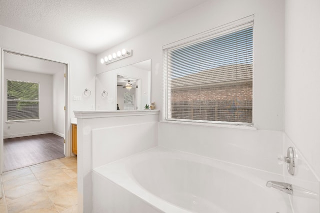 bathroom featuring vanity, tile patterned floors, ceiling fan, a washtub, and a textured ceiling