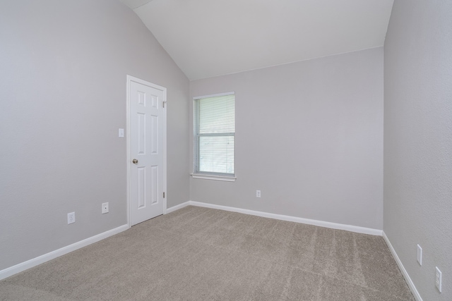 spare room featuring carpet flooring and lofted ceiling