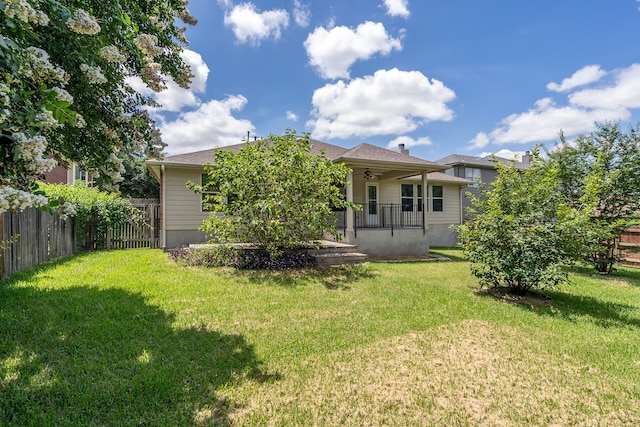 back of property featuring ceiling fan, a yard, and covered porch