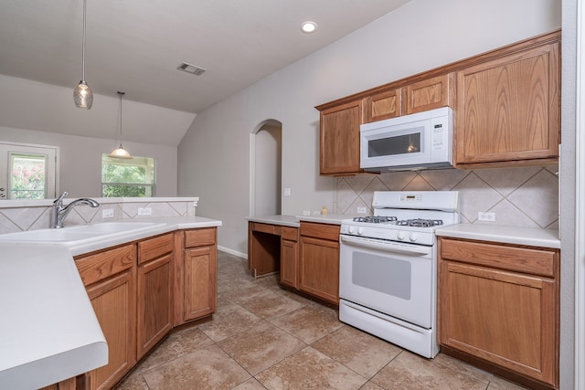 kitchen with backsplash, white appliances, vaulted ceiling, sink, and pendant lighting