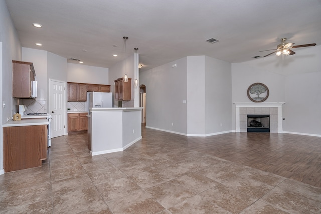 kitchen with ceiling fan, backsplash, pendant lighting, white appliances, and a kitchen island