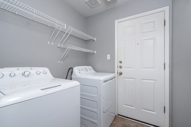 laundry room with washer and dryer and dark tile patterned flooring