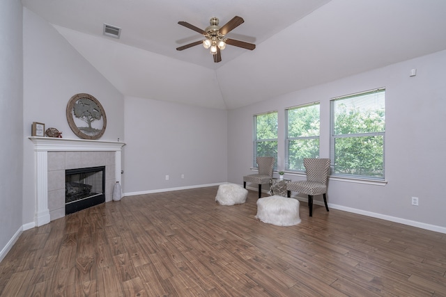 unfurnished room with a tile fireplace, ceiling fan, dark wood-type flooring, and lofted ceiling