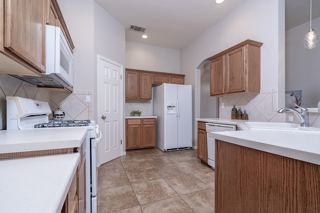 kitchen with tasteful backsplash, sink, pendant lighting, and white appliances