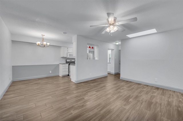 unfurnished living room featuring light wood-type flooring, a skylight, and ceiling fan with notable chandelier