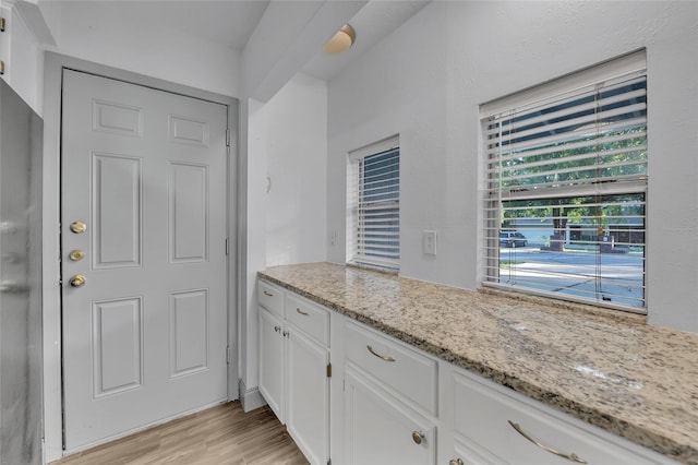 kitchen featuring white cabinets, light stone counters, and light hardwood / wood-style flooring