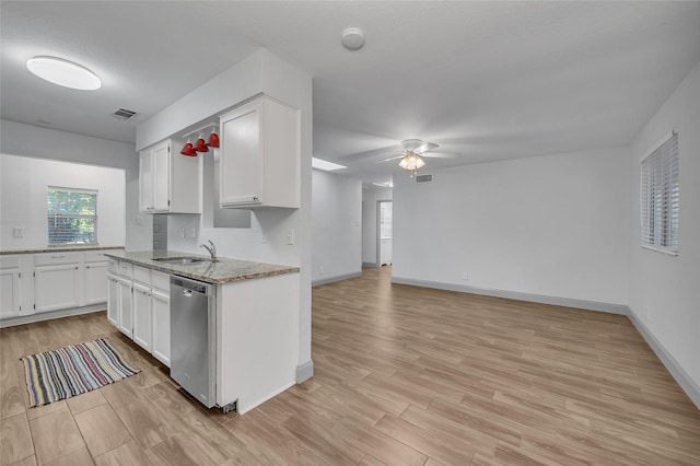 kitchen with light stone countertops, white cabinets, stainless steel dishwasher, and sink