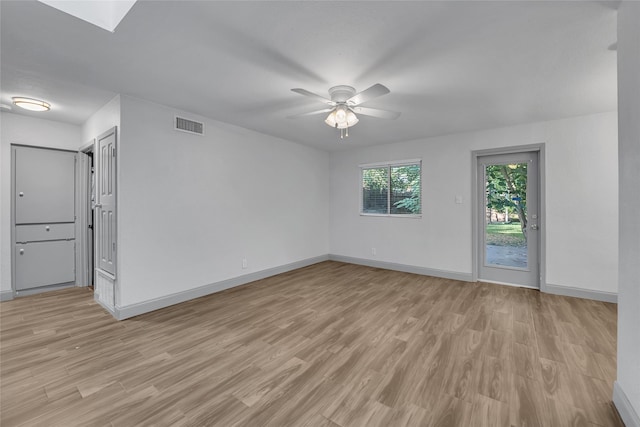 empty room with ceiling fan, a skylight, and light hardwood / wood-style flooring