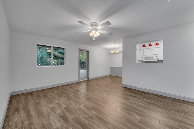 spare room featuring ceiling fan with notable chandelier and light hardwood / wood-style flooring