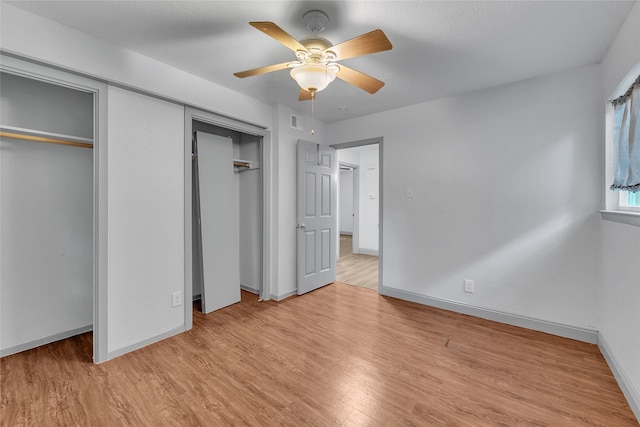 unfurnished bedroom featuring ceiling fan, two closets, and light hardwood / wood-style flooring