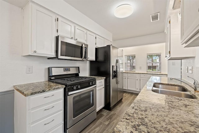 3411 Thomas Kincheon St, Austin, TX 78745 - kitchen featuring appliances with stainless steel finishes, white cabinetry, light stone counters, and a wainscoted wall